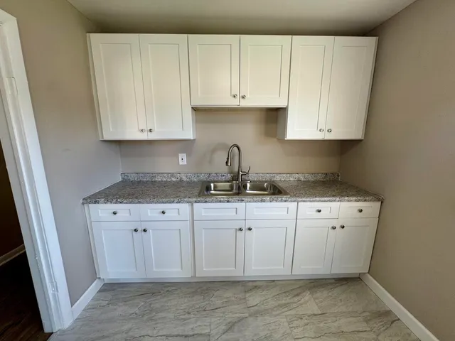 a kitchen with granite countertop white cabinets and sink