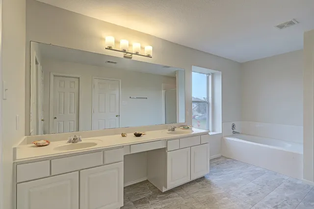 a bathroom with a tub a sink and mirror