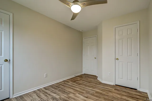 a view of a room with wooden floor and a ceiling fan