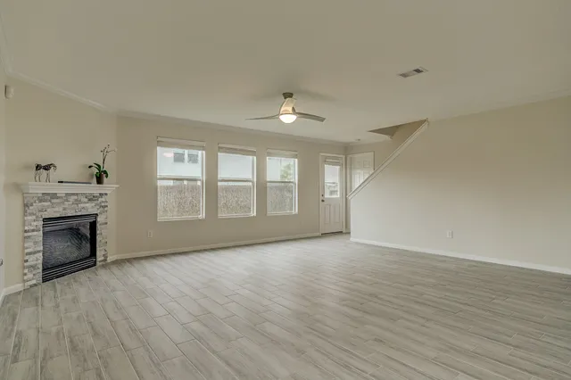an empty room with wooden floor fireplace and windows