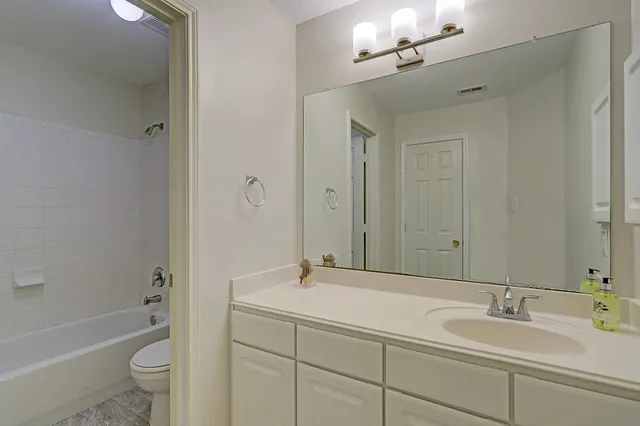 a bathroom with a double vanity sink toilet mirror and bathtub