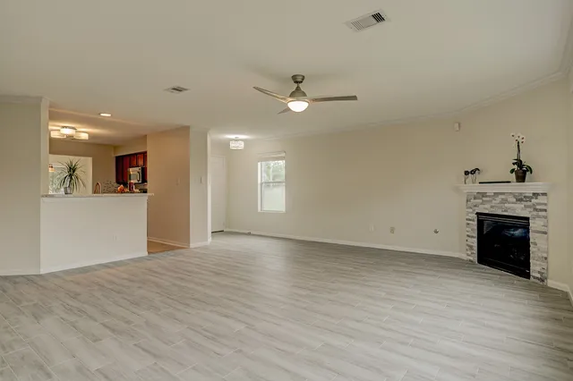 an empty room with wooden floor fireplace and windows