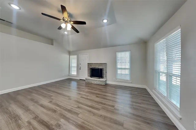 an empty room with wooden floor fan and windows