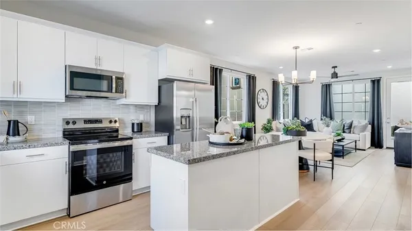 a kitchen with stainless steel appliances granite countertop a stove top oven a sink dishwasher a dining table and chairs with wooden floor