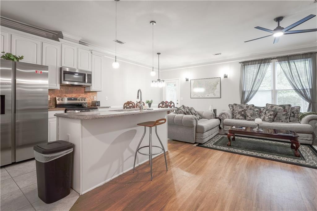 5331 Sherwin Drive Norcross, GA 30093 - Photo 5 of 29 a living room with stainless steel appliances kitchen island granite countertop furniture a rug a fireplace and a large window