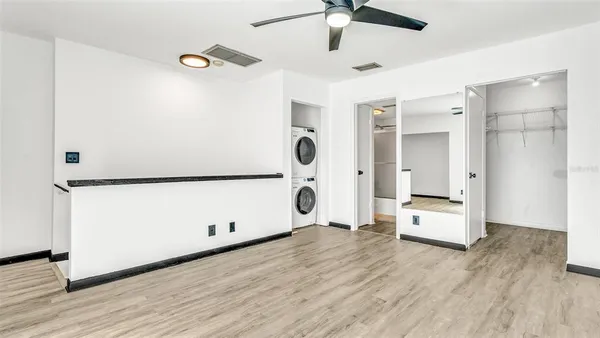 a view of an empty room with wooden floor and a ceiling fan