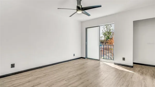 an empty room with wooden floor cabinet and windows