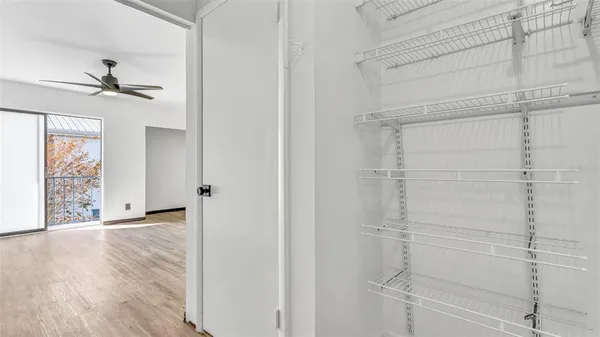 a view of empty room with wooden floor and fan
