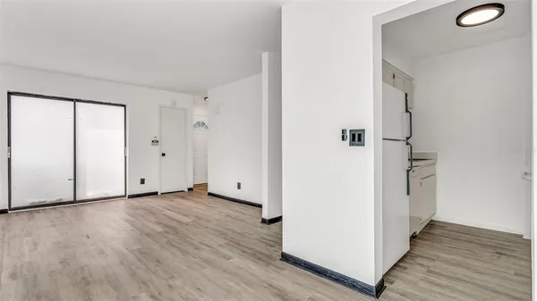 a view of an empty room with wooden floor and a window