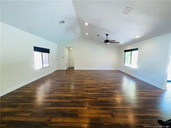 an empty room with windows and ceiling fan