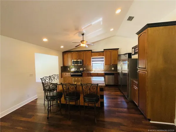 a kitchen with stainless steel appliances a dining table chairs and wooden floor