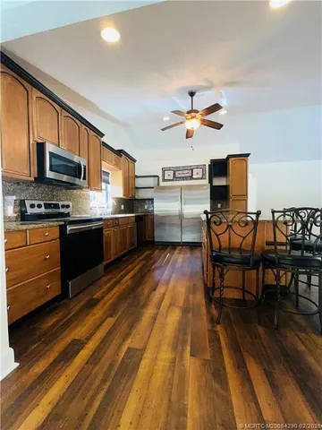 a kitchen with stainless steel appliances granite countertop a stove top oven a sink dishwasher a dining table and chairs with wooden floor