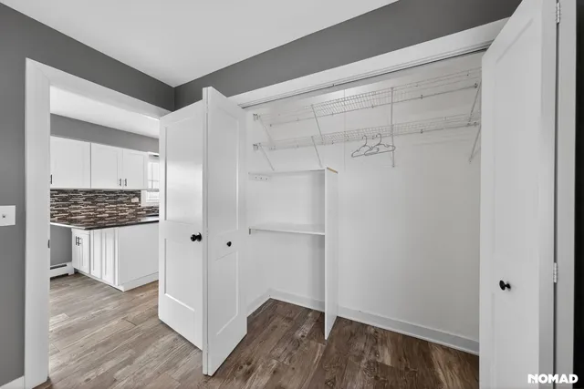 a view of walk in closet with hardwood floor