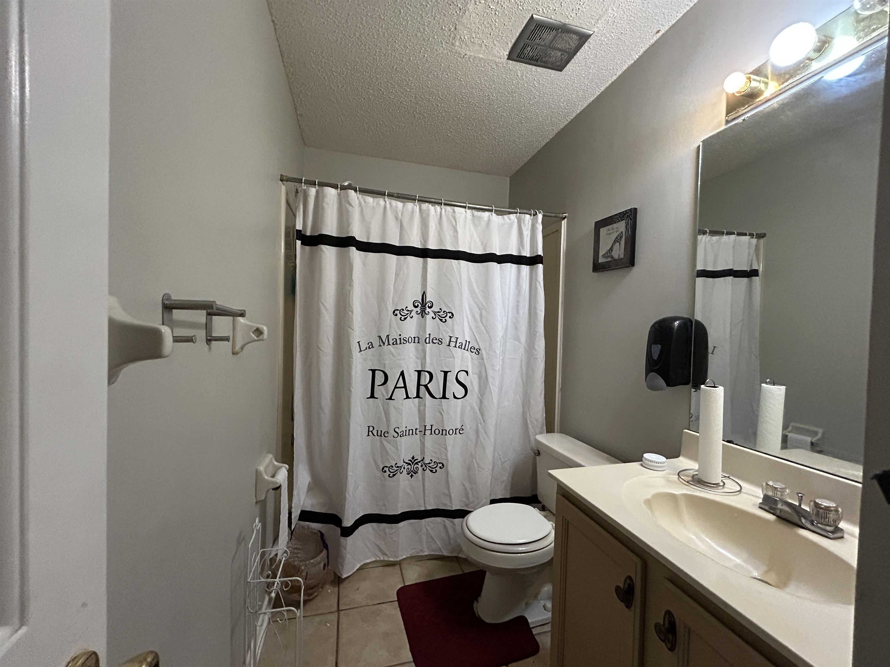 741 North Sanga Road Memphis, TN 38018 - Photo 6 of 13 Bathroom featuring vanity, a textured ceiling, light tile patterned flooring, and shower / bathtub combination with curtain