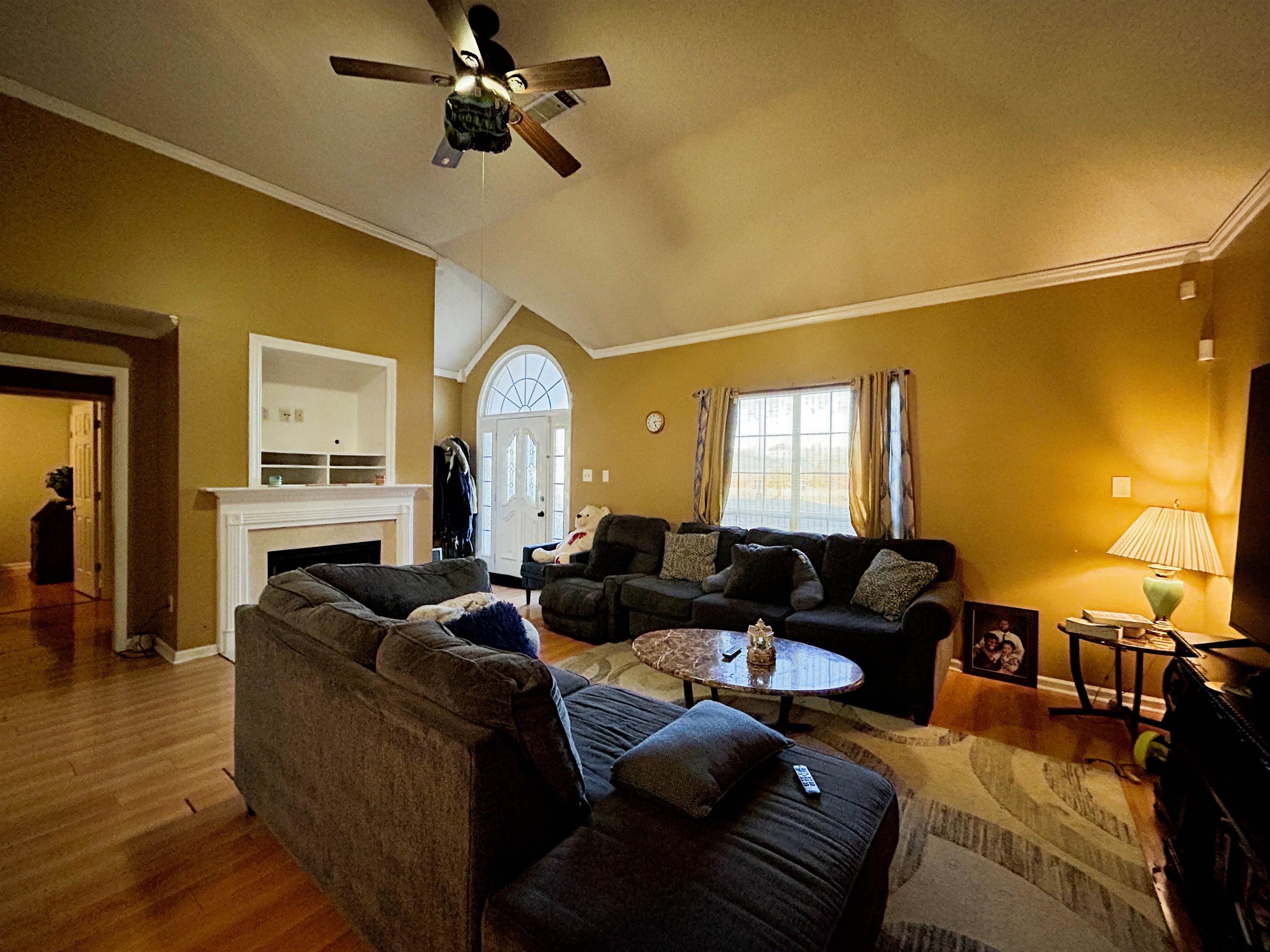 741 North Sanga Road Memphis, TN 38018 - Photo 10 of 13 Living room featuring crown molding, wood finished floors, a ceiling fan, vaulted ceiling, and a fireplace