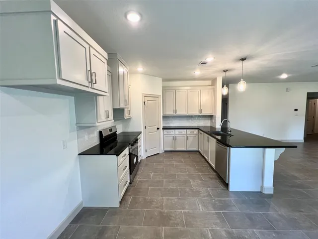 a large kitchen with stainless steel appliances kitchen island granite countertop a sink and cabinets