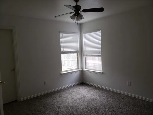 an empty room with windows and chandelier fan
