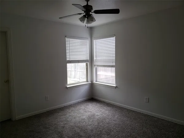 an empty room with windows and chandelier fan