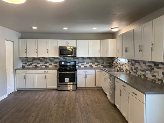 a kitchen with granite countertop white cabinets and stainless steel appliances