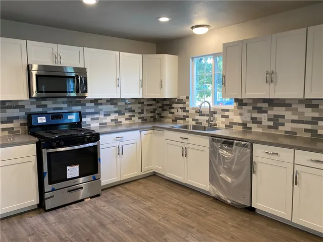 a kitchen with stainless steel appliances granite countertop a stove a sink and a microwave
