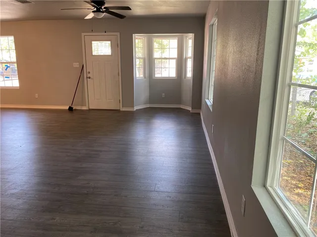 an empty room with wooden floor and windows