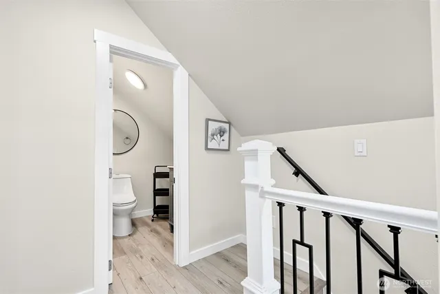 a view of a hallway with bathroom and wooden floor