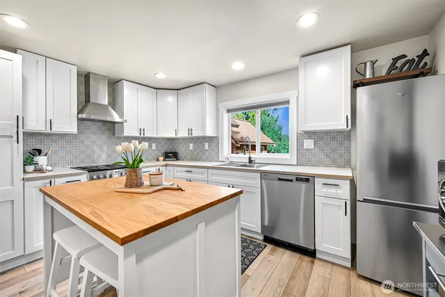 a kitchen with stainless steel appliances granite countertop a refrigerator a sink and a stove