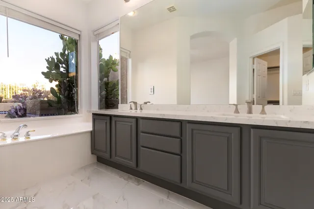 a bathroom with a double vanity sink large mirror and a bathtub