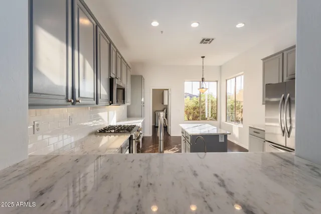 a kitchen with stainless steel appliances granite countertop a refrigerator oven a sink dishwasher and a stove with wooden floor