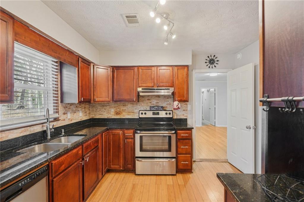 1145 Christian Circle Southeast Conyers, GA 30013 - Photo 8 of 18 a kitchen with stainless steel appliances granite countertop wooden cabinets a sink dishwasher a stove and a refrigerator with wooden floor