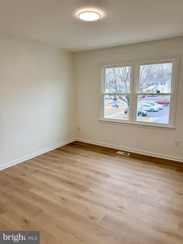 an empty room with wooden floor and window