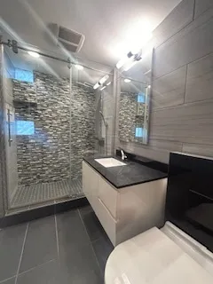a bathroom with a granite countertop sink a toilet and shower