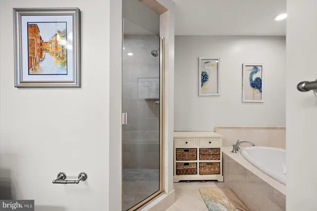 a bathroom with a glass shower door a bathtub a sink and a mirror