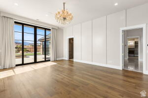 1141 East Lost Ridge Drive Washington, UT 84780 - Photo 60 of 108 Spacious room featuring wood-finish flooring, a large glass multi-panel door with mountain scenery, a decorative chandelier, recessed lighting, and white panel accent walls