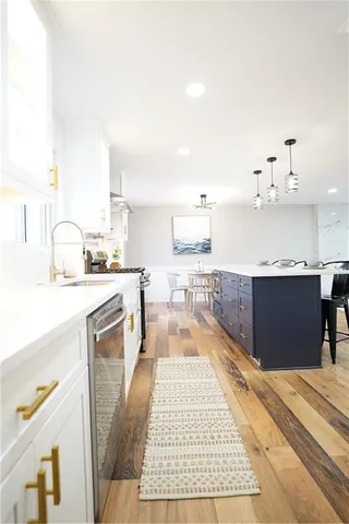 a kitchen with kitchen island a counter top space a sink a stove and cabinets
