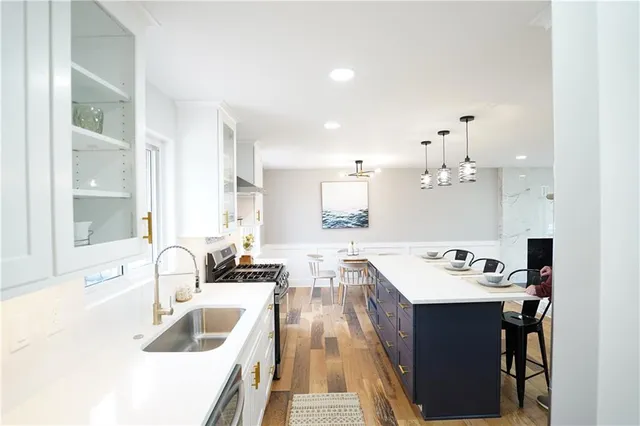 a kitchen with a sink dishwasher a stove and white countertops with wooden floor