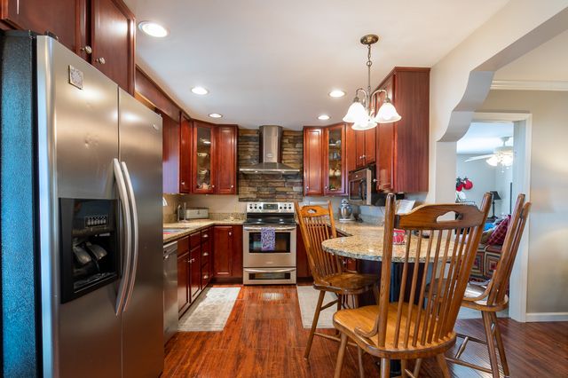 a kitchen with stainless steel appliances kitchen island granite countertop a refrigerator a stove a sink a dining table and chairs