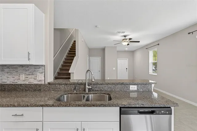 a kitchen with stainless steel appliances granite countertop white cabinets a refrigerator a sink a stove a microwave and white cabinets