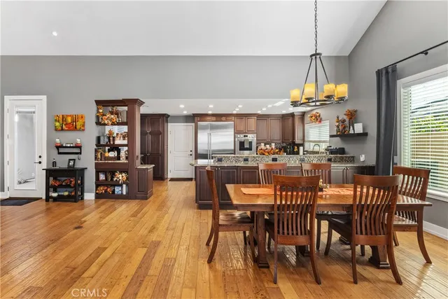 a dining room with stainless steel appliances a table chairs and a chandelier