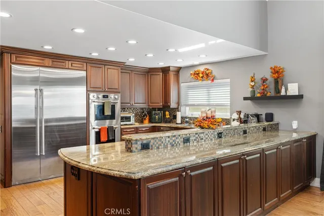 a kitchen with stainless steel appliances granite countertop a sink a stove and a refrigerator