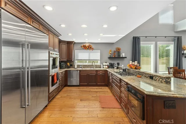 a large kitchen with stainless steel appliances granite countertop a sink and a refrigerator