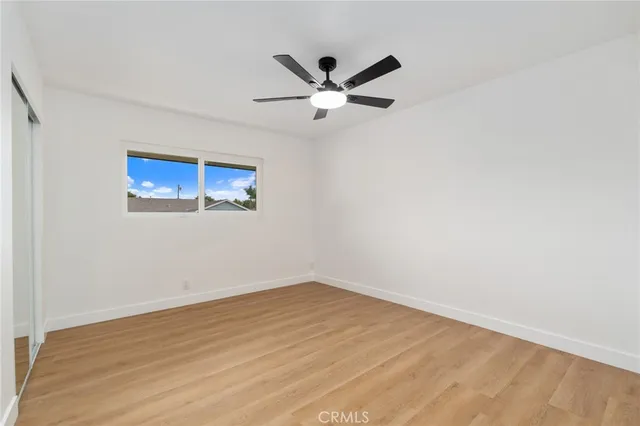 an empty room with wooden floor and ceiling fan