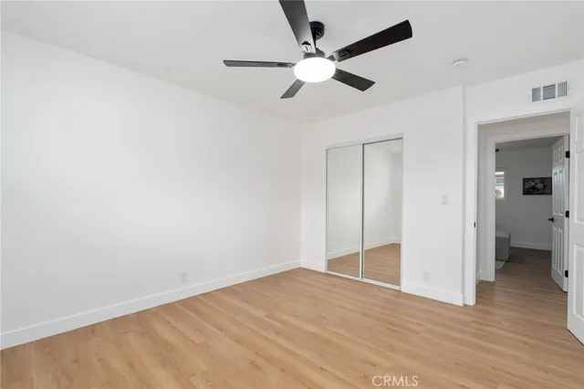 an empty room with wooden floor and fan