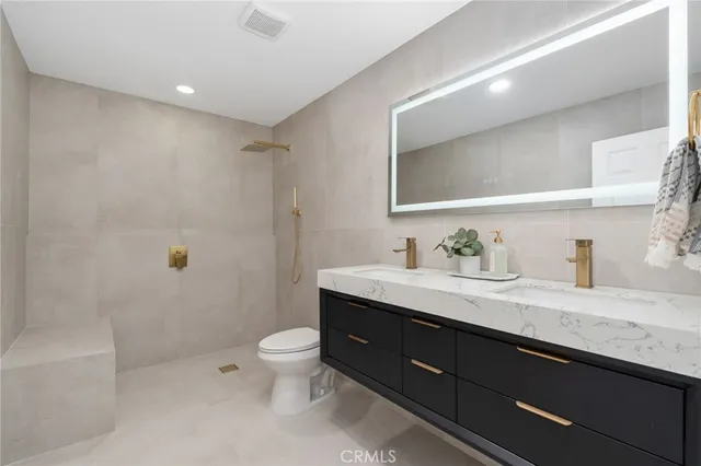 a bathroom with a granite countertop sink a toilet a mirror and shower