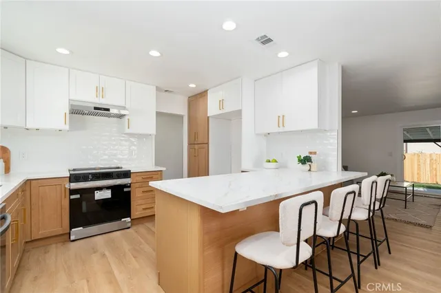 a kitchen with kitchen island a stove a table and chairs in it