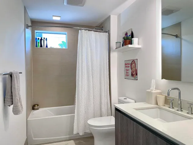 a bathroom with a granite countertop sink a toilet a shower curtain and a bath tub