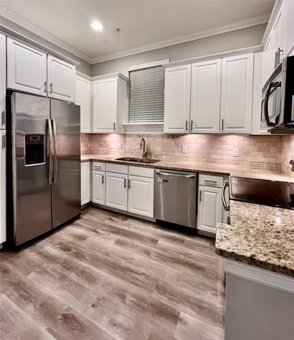 a kitchen with stainless steel appliances granite countertop a refrigerator a stove and a sink with wooden floor