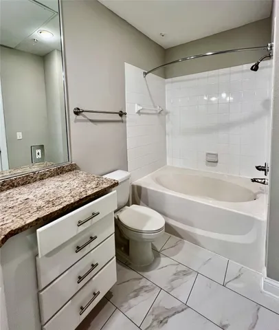 a bathroom with a granite countertop sink a toilet a mirror and bathtub