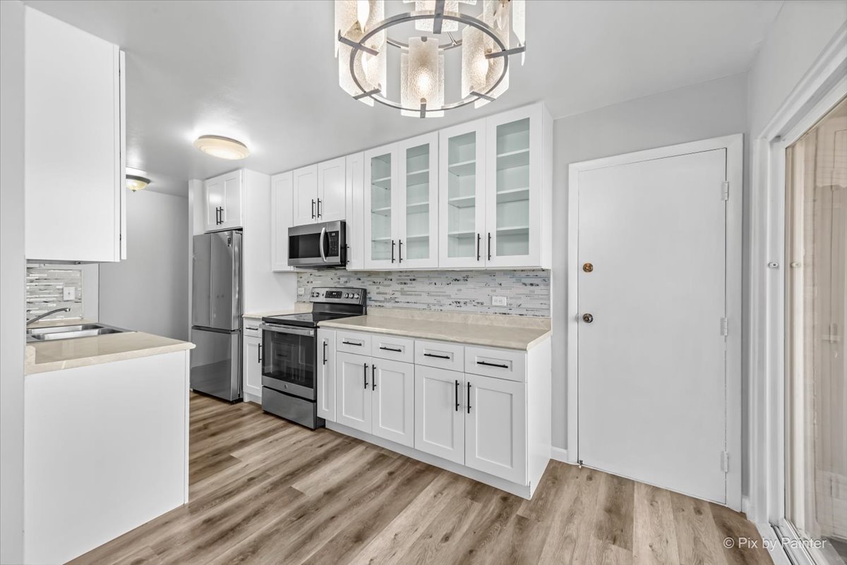 681 Elmhurst Road, Unit E Mount Prospect, IL 60056 - Photo 7 of 20 a kitchen with stainless steel appliances granite countertop a stove top oven a sink and a refrigerator