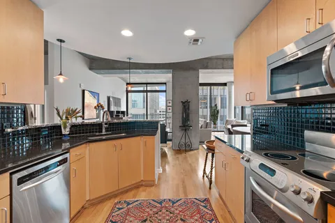 a view of a kitchen with kitchen island granite countertop a sink and a refrigerator